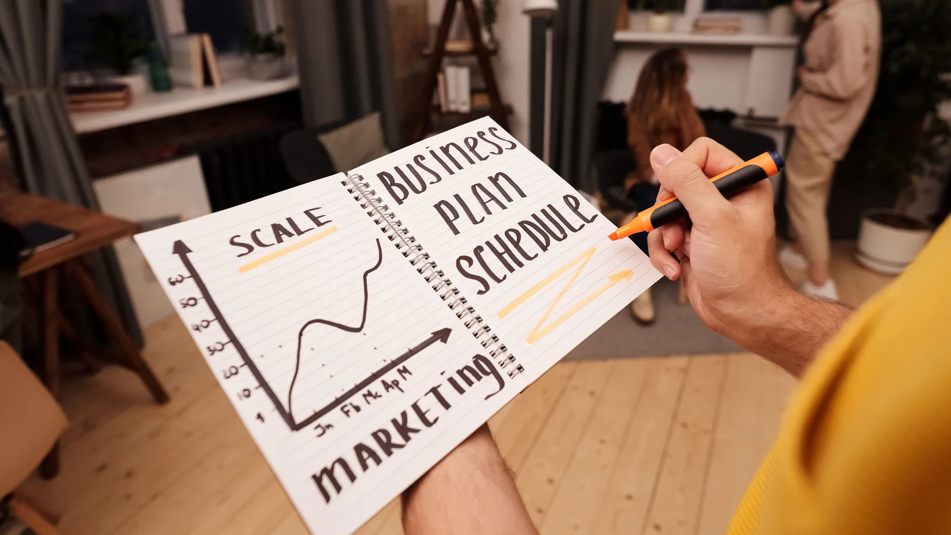 A person writing a business plan in a notebook